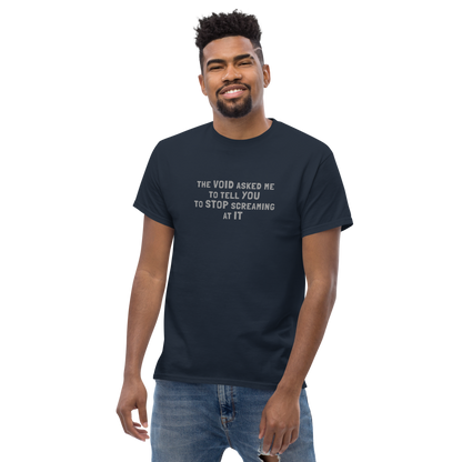 "The Void asked me to tell you to stop screaming at it" printed on a navy unisex classic tee worn by a male