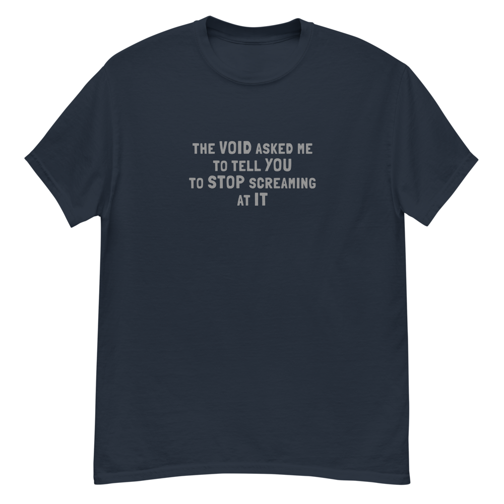 "The Void asked me to tell you to stop screaming at it" printed on a navy unisex classic tee laying on a flat surface