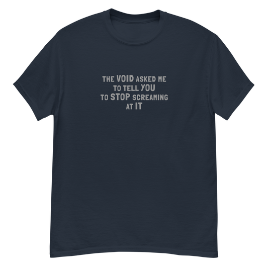 "The Void asked me to tell you to stop screaming at it" printed on a navy unisex classic tee laying on a flat surface