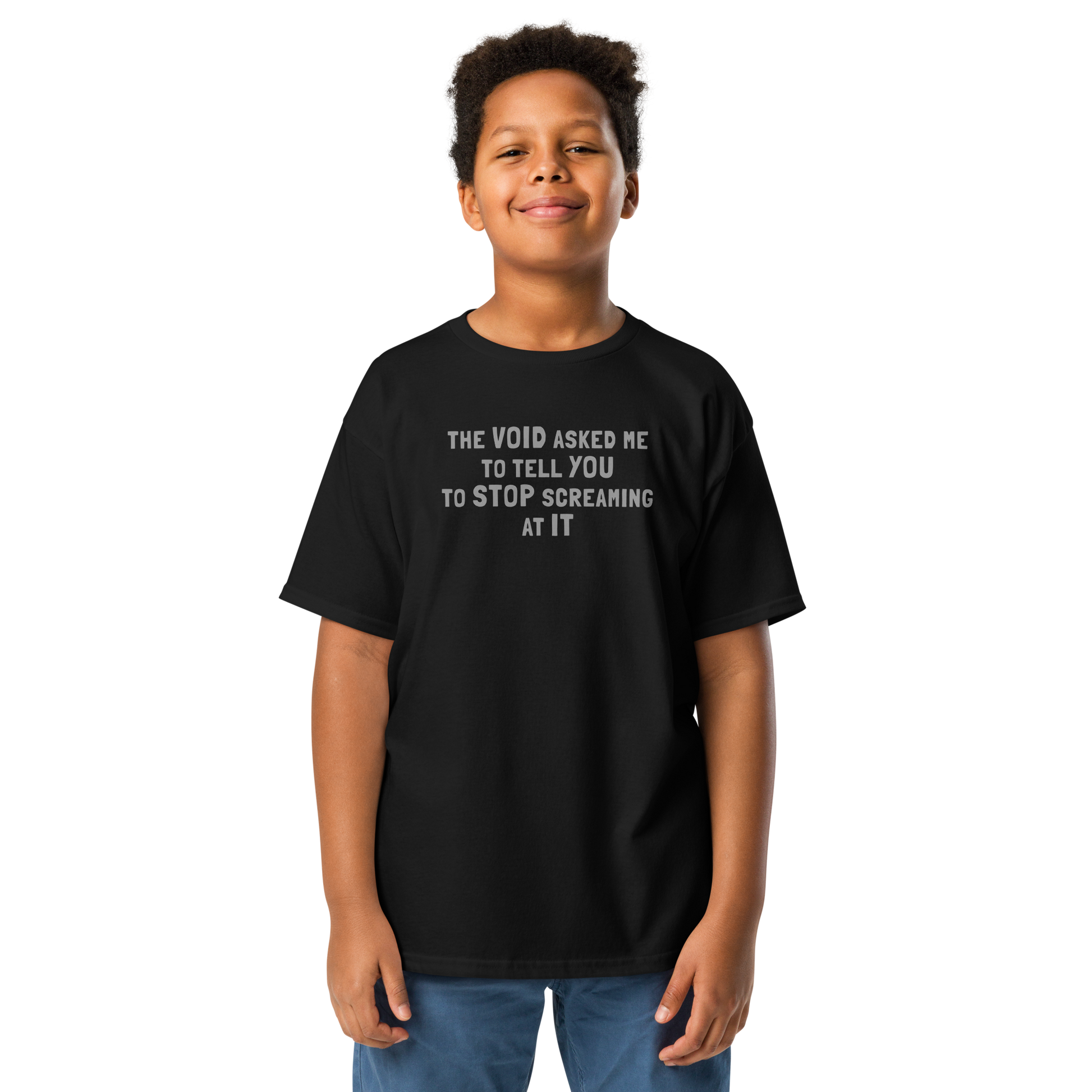 "The Void asked me to tell you to stop screaming at it" printed on a black youth classic tee worn by a male