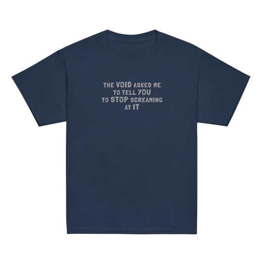 "The Void asked me to tell you to stop screaming at it" printed on a navy youth classic tee laying on a flat surface