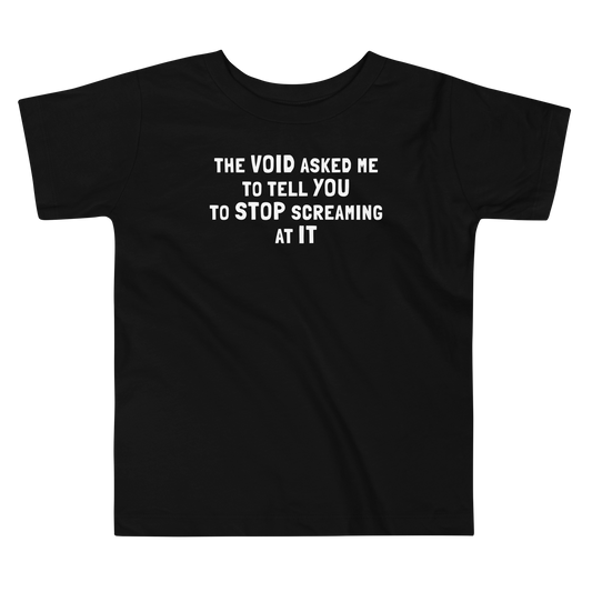 "The Void asked me to tell you to stop screaming at it" printed on a black toddler short sleeve tee laying on a flat surface