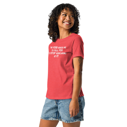 "The Void asked me to tell you to stop screaming at it" printed on a heather red women's relaxed t-shirt worn by a female