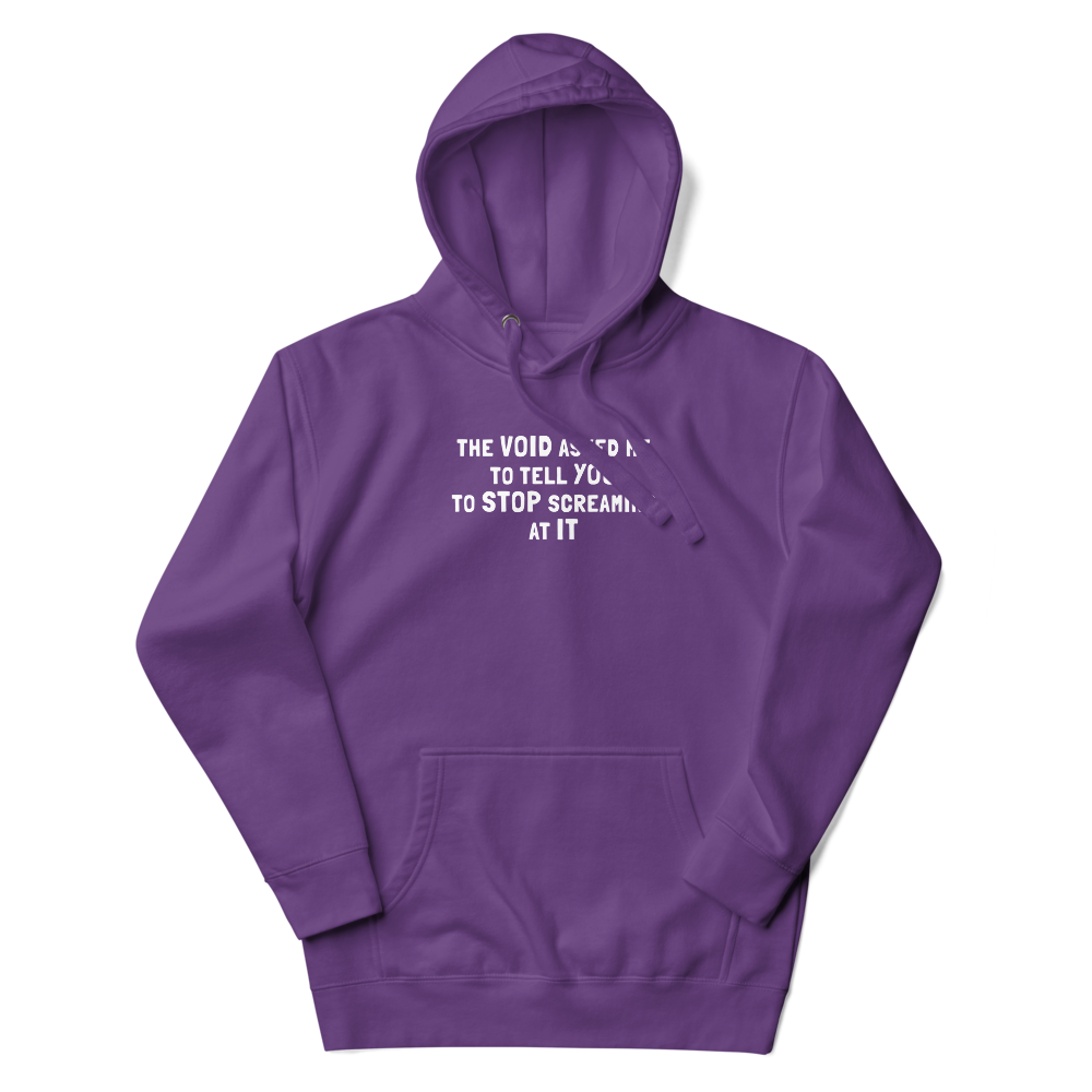 "The Void asked me to tell you to stop screaming at it" printed on a purple unisex hoodie laying on a flat surface with the hood up