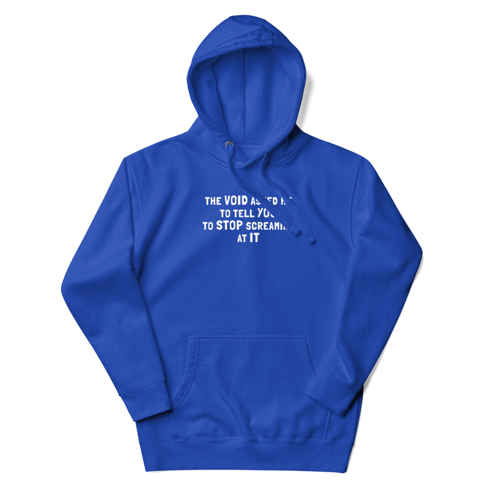 "The Void asked me to tell you to stop screaming at it" printed on a team royal unisex hoodie laying on a flat surface with the hood up