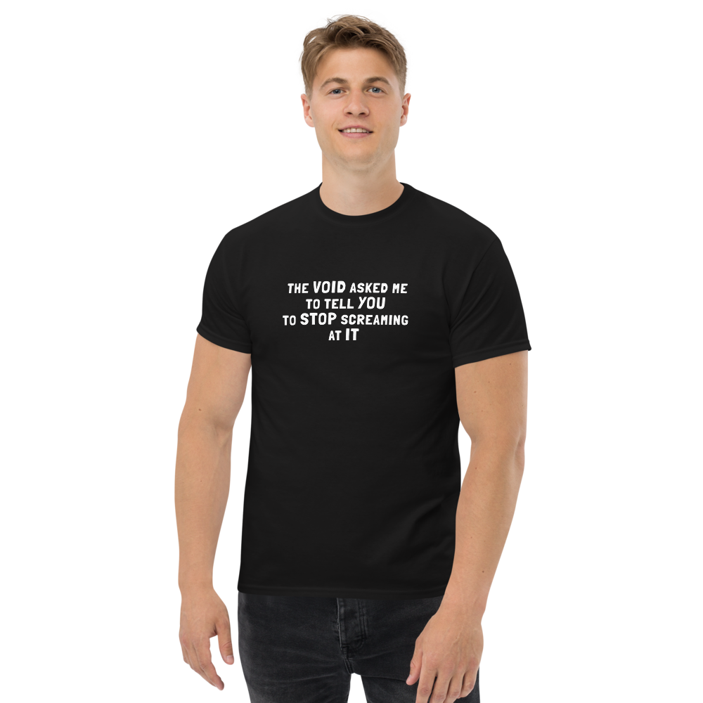 "The Void asked me to tell you to stop screaming at it" printed on a black unisex classic tee worn by a male