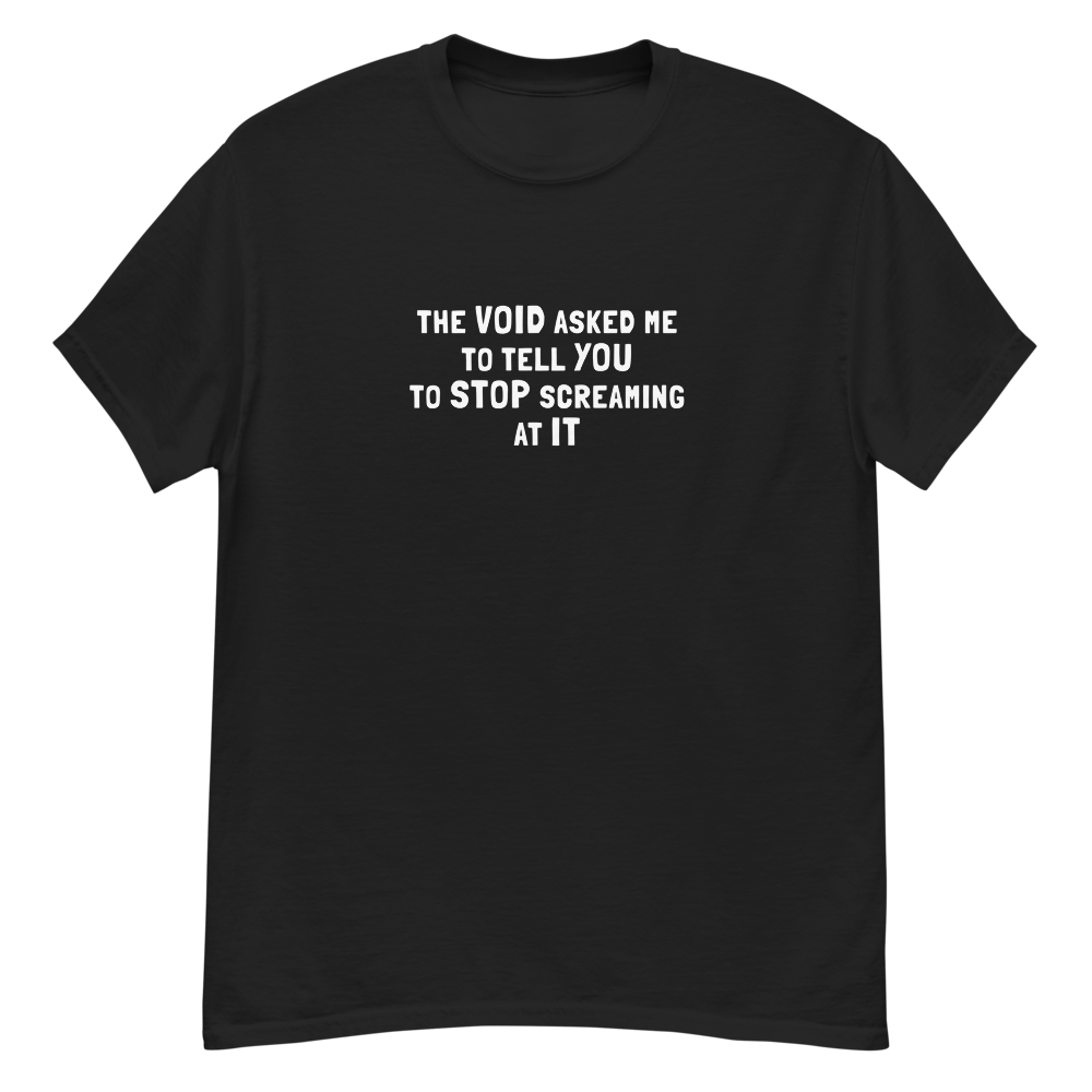"The Void asked me to tell you to stop screaming at it" printed on a black unisex classic tee laying on a flat surface