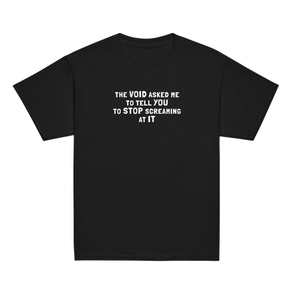 "The Void asked me to tell you to stop screaming at it" printed on a black youth classic tee laying on a flat surface
