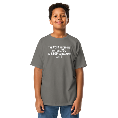 "The Void asked me to tell you to stop screaming at it" printed on a charcoal youth classic tee worn by a male