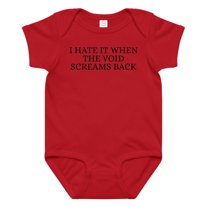 "I hate it when the void screams back" printed on a red baby jersey bodysuit laying on a flat surface amongst other clothes