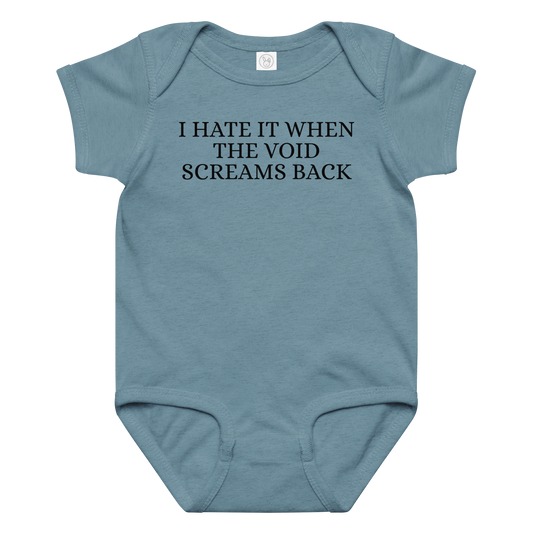 "I hate it when the void screams back" printed on a vintage indigo baby jersey bodysuit laying on a flat surface amongst other clothes