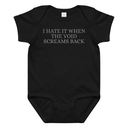 "I hate it when the void screams back" printed on a black baby jersey bodysuit laying on a flat surface amongst other clothes