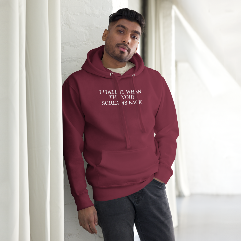 "I hate it when the void screams back" printed on a maroon unisex hoodie worn by a male