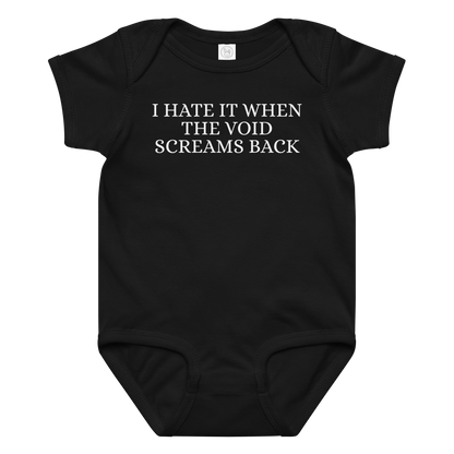 "I hate it when the void screams back" printed on a black baby jersey bodysuit laying on a flat surface amongst other clothes