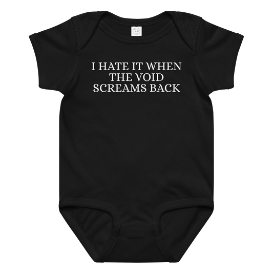 "I hate it when the void screams back" printed on a black baby jersey bodysuit laying on a flat surface amongst other clothes
