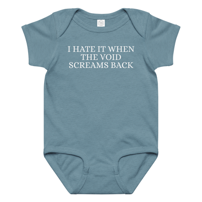 "I hate it when the void screams back" printed on a vintage indigo baby jersey bodysuit laying on a flat surface amongst other clothes