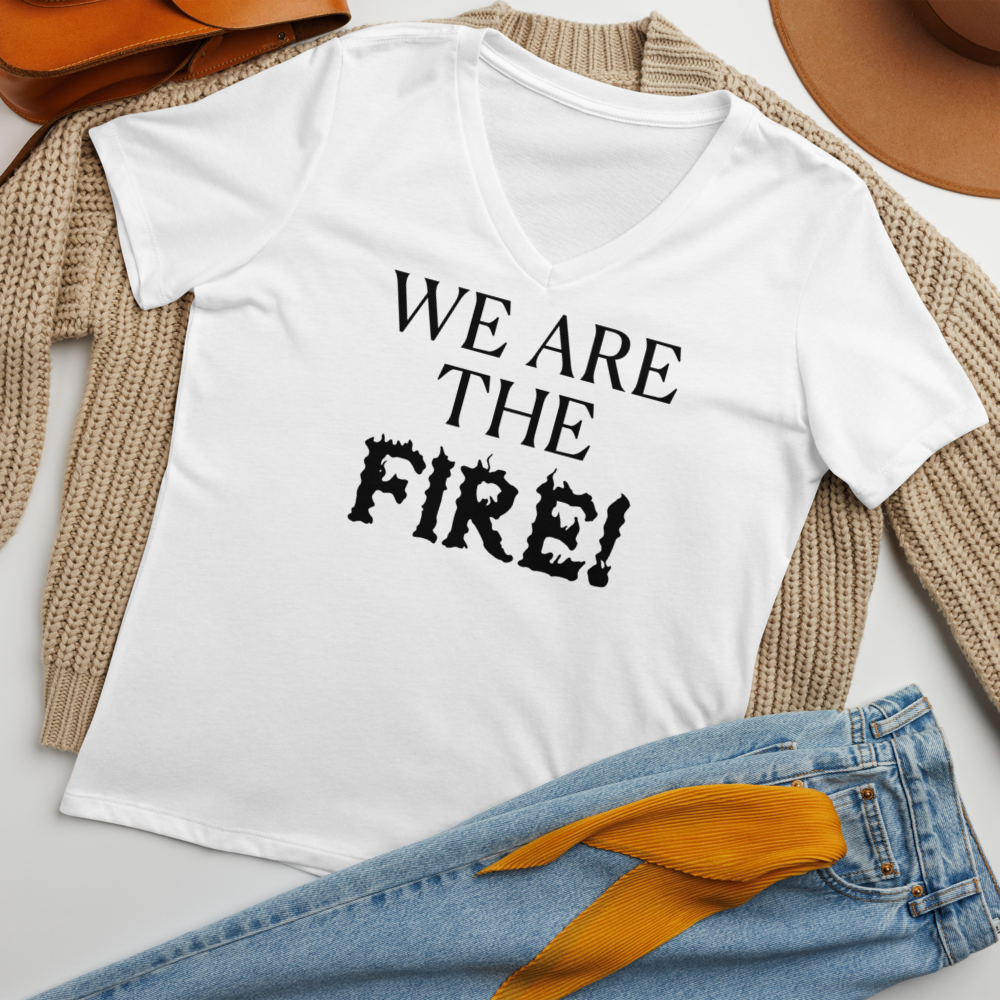 "We are the fire!" printed on a solid white blend women's relaxed v-neck t-shirt laying on a flat surface amongst other clothes
