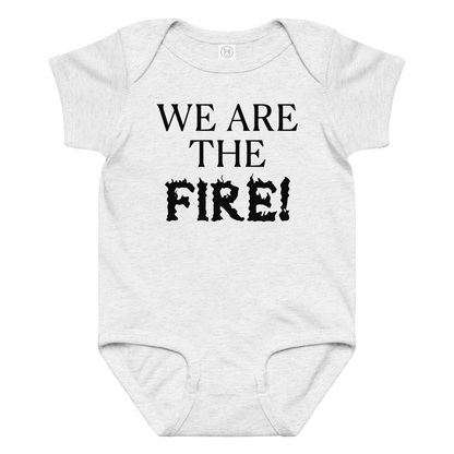"We are the fire!" printed on a ash baby jersey bodysuit laying on a flat surface amongst other clothes