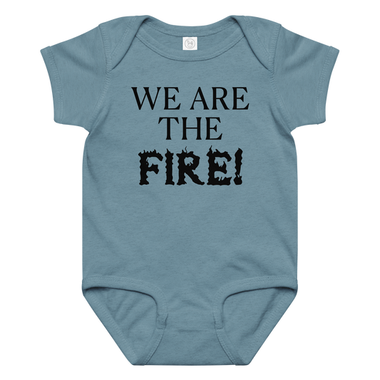 "We are the fire!" printed on a vintage indigo baby jersey bodysuit laying on a flat surface amongst other clothes