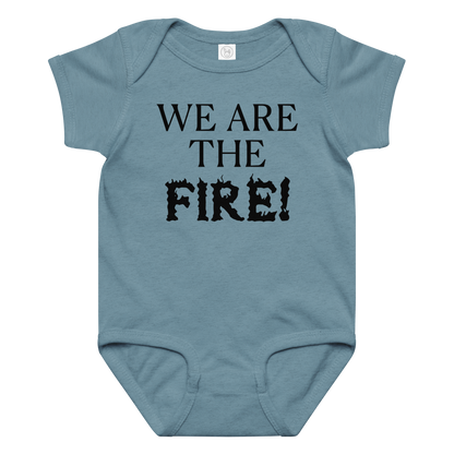 "We are the fire!" printed on a vintage indigo baby jersey bodysuit laying on a flat surface amongst other clothes