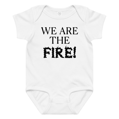 "We are the fire!" printed on a white baby jersey bodysuit laying on a flat surface amongst other clothes