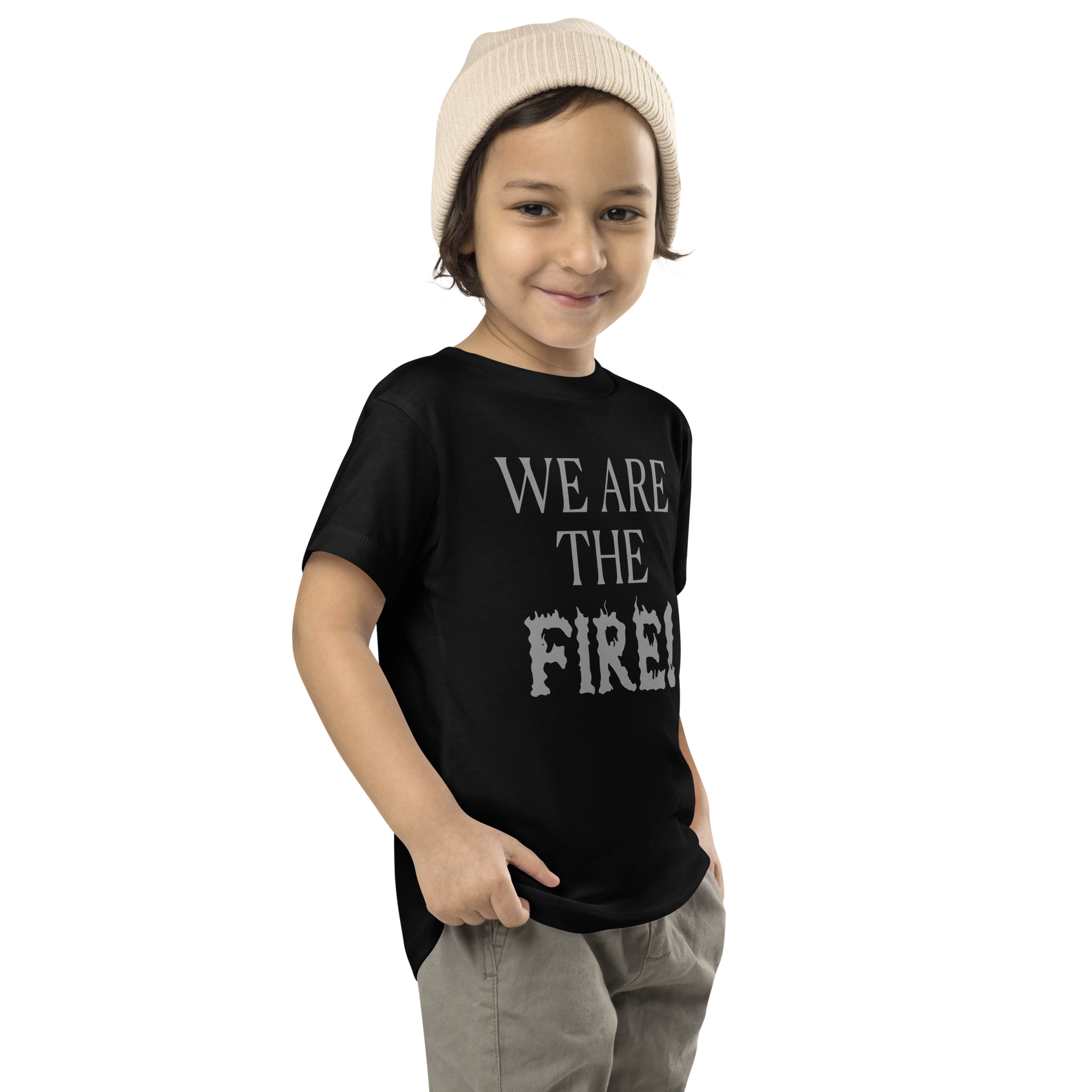 "We are the fire!" printed on a black toddler short sleeve tee worn by a male who is also wearing a knit cap