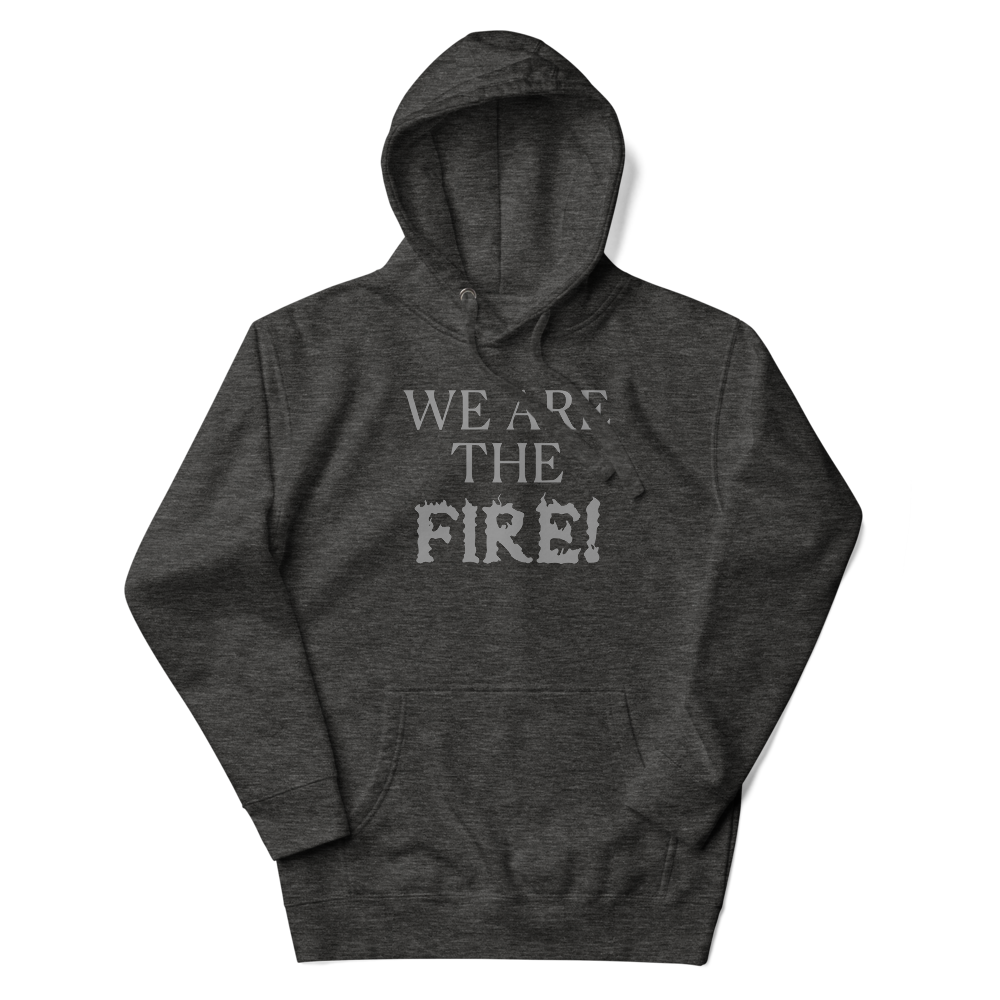 "We are the fire!" printed on a charcoal heather unisex hoodie laying on a flat surface with the hood up