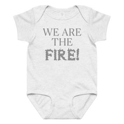 "We are the fire!" printed on a ash baby jersey bodysuit laying on a flat surface amongst other clothes
