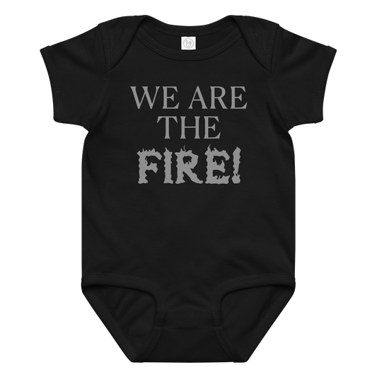 "We are the fire!" printed on a black baby jersey bodysuit laying on a flat surface amongst other clothes