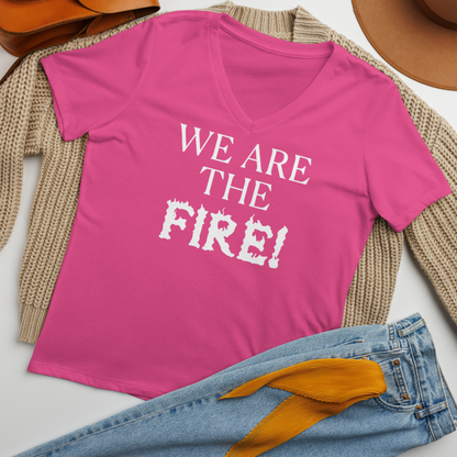"We are the fire!" printed on a berry women's relaxed v-neck t-shirt laying on a flat surface amongst other clothes