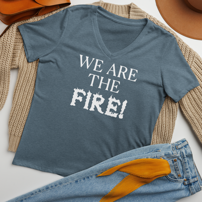 "We are the fire!" printed on a heather slate women's relaxed v-neck t-shirt laying on a flat surface amongst other clothes