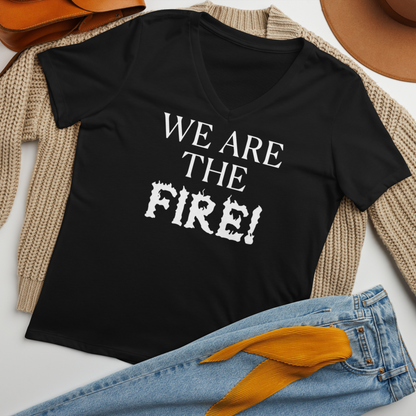 "We are the fire!" printed on a solid black blend women's relaxed v-neck t-shirt laying on a flat surface amongst other clothes