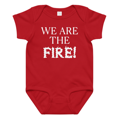 "We are the fire!" printed on a red baby jersey bodysuit laying on a flat surface amongst other clothes