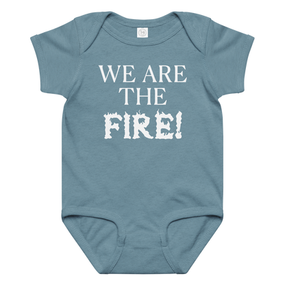 "We are the fire!" printed on a vintage indigo baby jersey bodysuit laying on a flat surface amongst other clothes