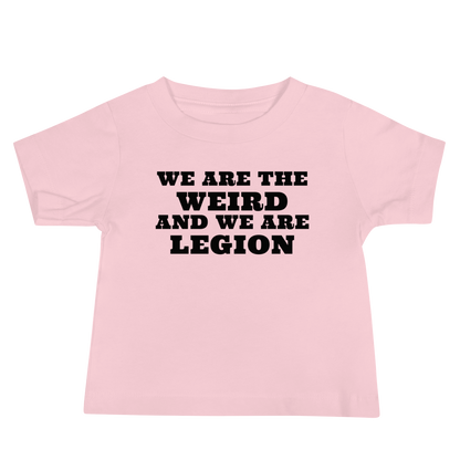 "We are the weird and we are legion" printed on a pink baby jersey short sleeve tee laying on a flat surface