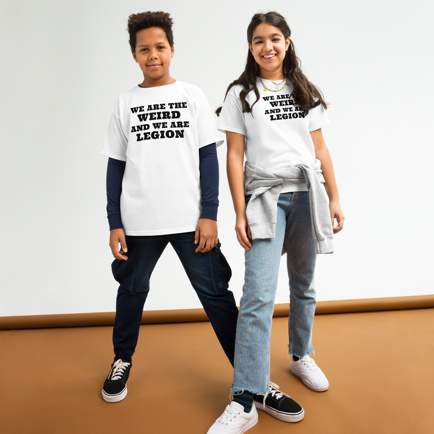 "We are the weird and we are legion" printed on a white youth classic tee worn by a female and male