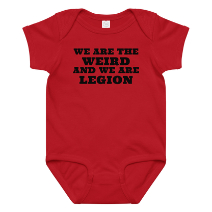 "We are the weird and we are legion" printed on a red baby jersey bodysuit laying on a flat surface amongst other clothes