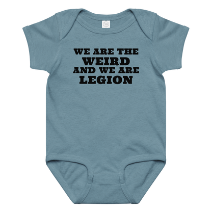 "We are the weird and we are legion" printed on a vintage indigo baby jersey bodysuit laying on a flat surface amongst other clothes