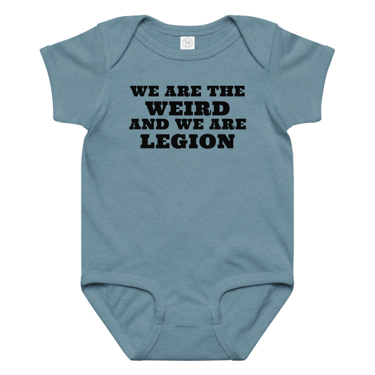"We are the weird and we are legion" printed on a vintage indigo baby jersey bodysuit laying on a flat surface amongst other clothes