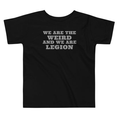"We are the weird and we are legion" printed on a black toddler short sleeve tee laying on a flat surface