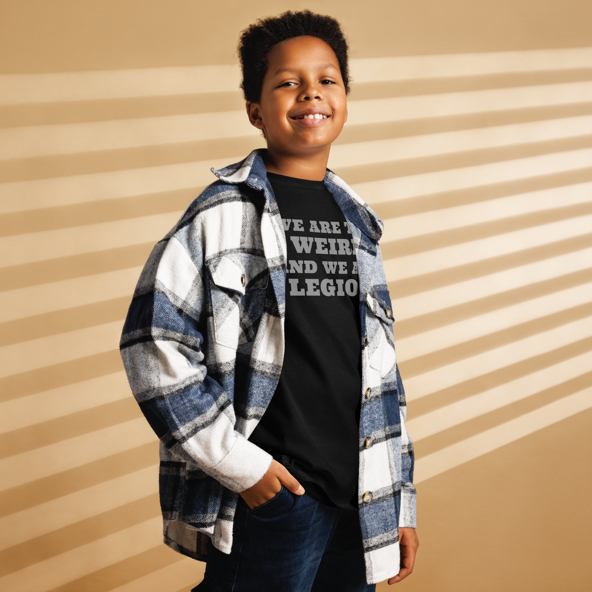 "We are the weird and we are legion" printed on a black youth classic tee worn by a male also wearing a jacket