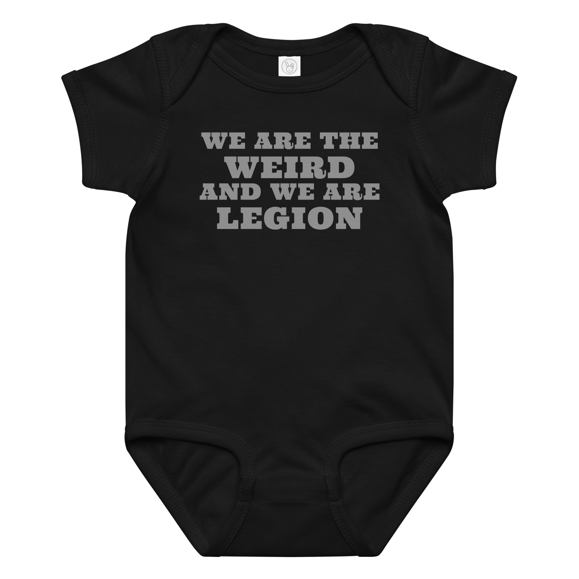 "We are the weird and we are legion" printed on a black baby jersey bodysuit laying on a flat surface amongst other clothes