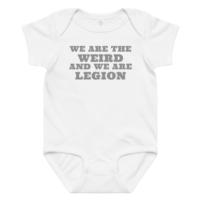 "We are the weird and we are legion" printed on a white baby jersey bodysuit laying on a flat surface amongst other clothes