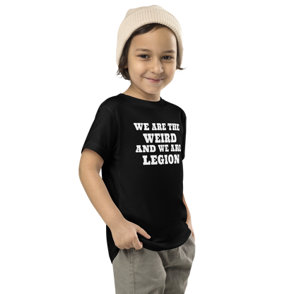 "We are the weird and we are legion" printed on a black toddler short sleeve tee worn by a male who is also wearing a knit cap