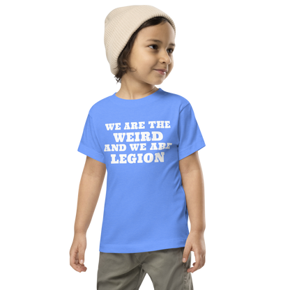 "We are the weird and we are legion" printed on a heather columbia blue toddler short sleeve tee worn by a male wearing a cap