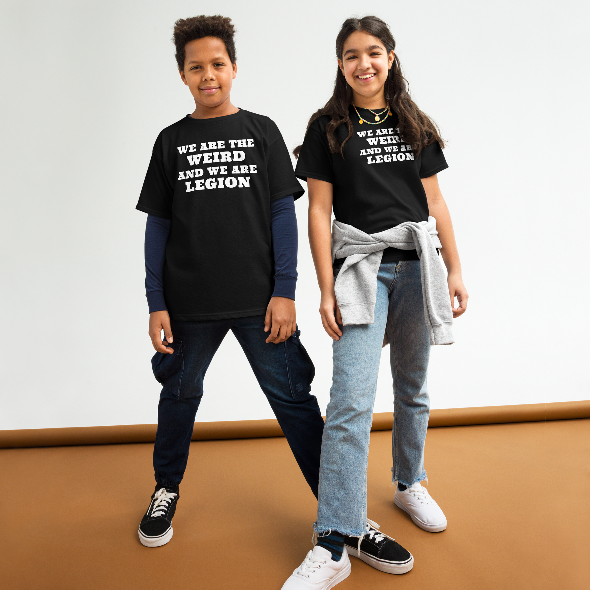 "We are the weird and we are legion" printed on a black youth classic tee worn by a female and male