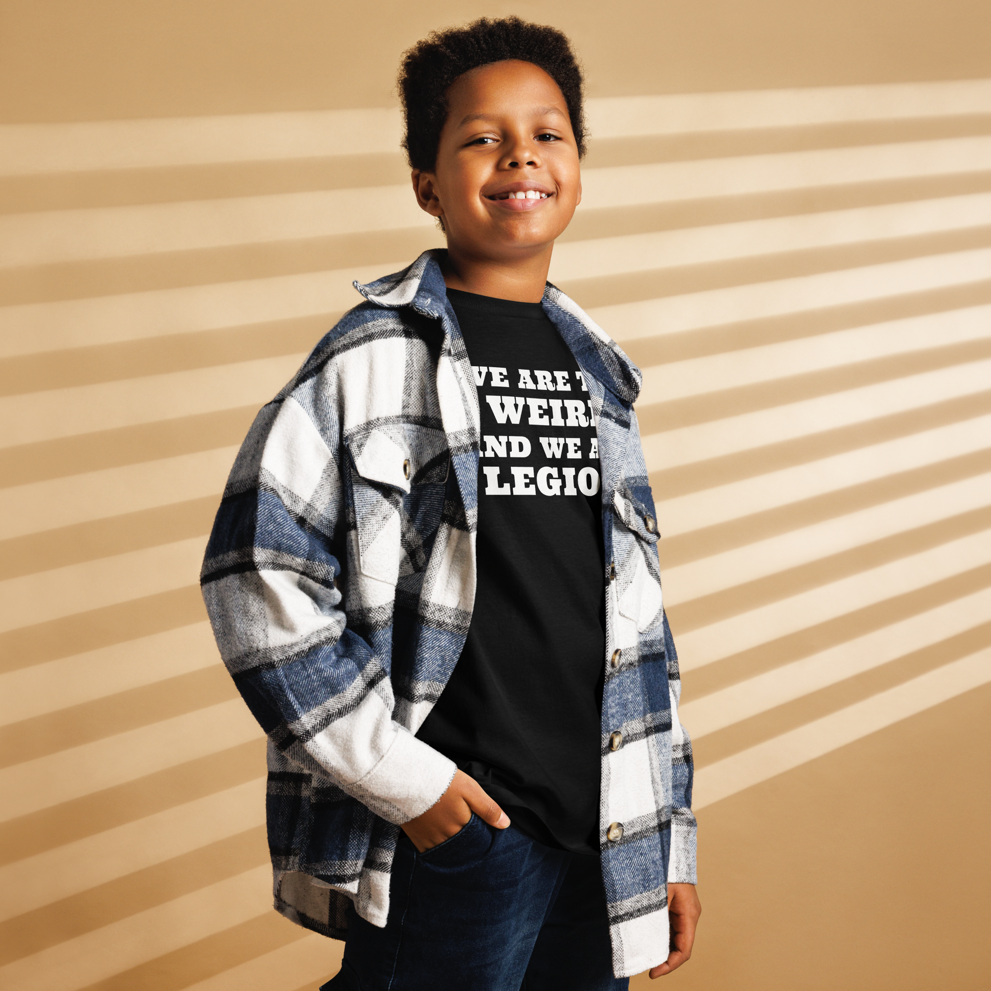 "We are the weird and we are legion" printed on a black youth classic tee worn by a male also wearing a jacket