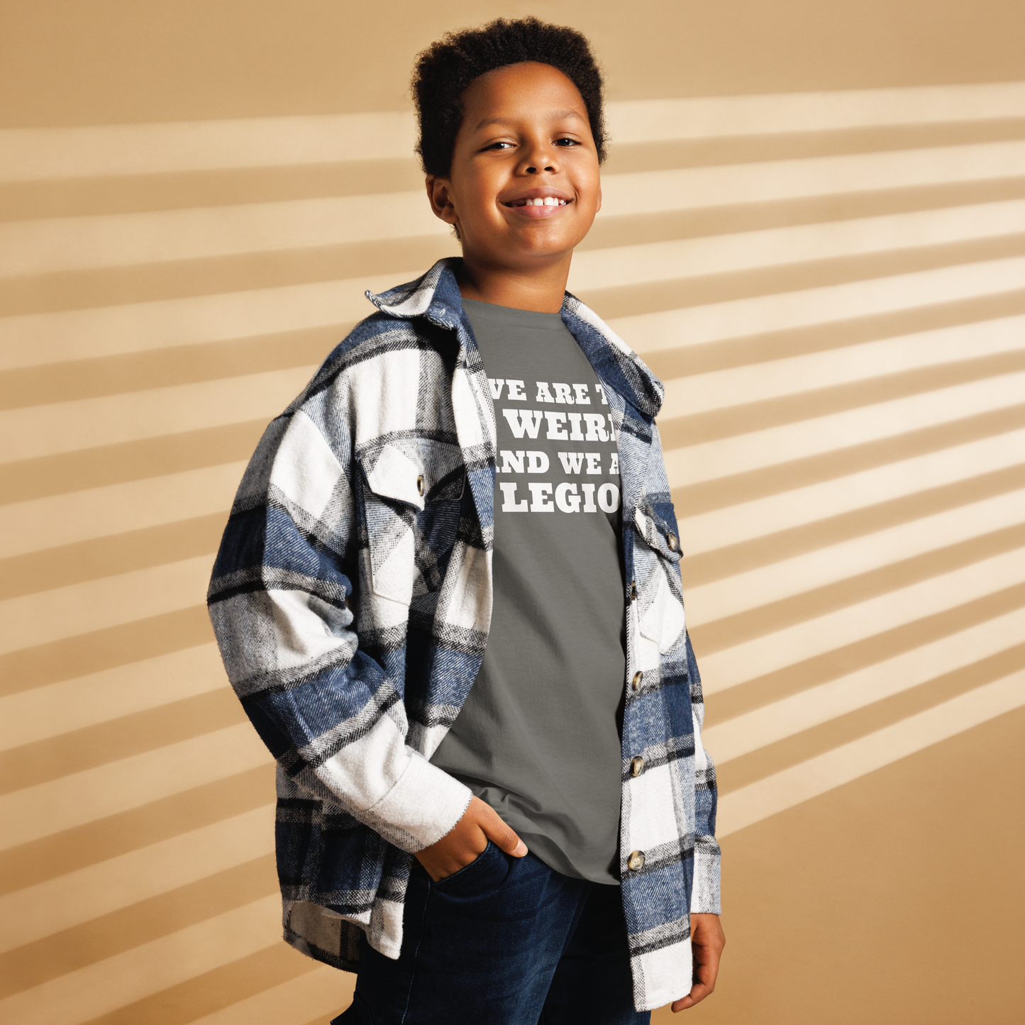 "We are the weird and we are legion" printed on a charcoal youth classic tee worn by a male also wearing a jacket