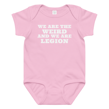 "We are the weird and we are legion" printed on a pink baby jersey bodysuit laying on a flat surface amongst other clothes