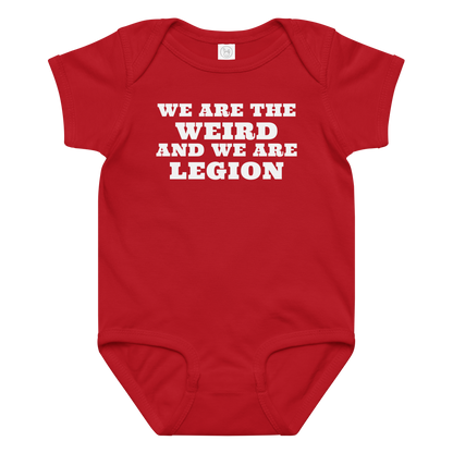 "We are the weird and we are legion" printed on a red baby jersey bodysuit laying on a flat surface amongst other clothes